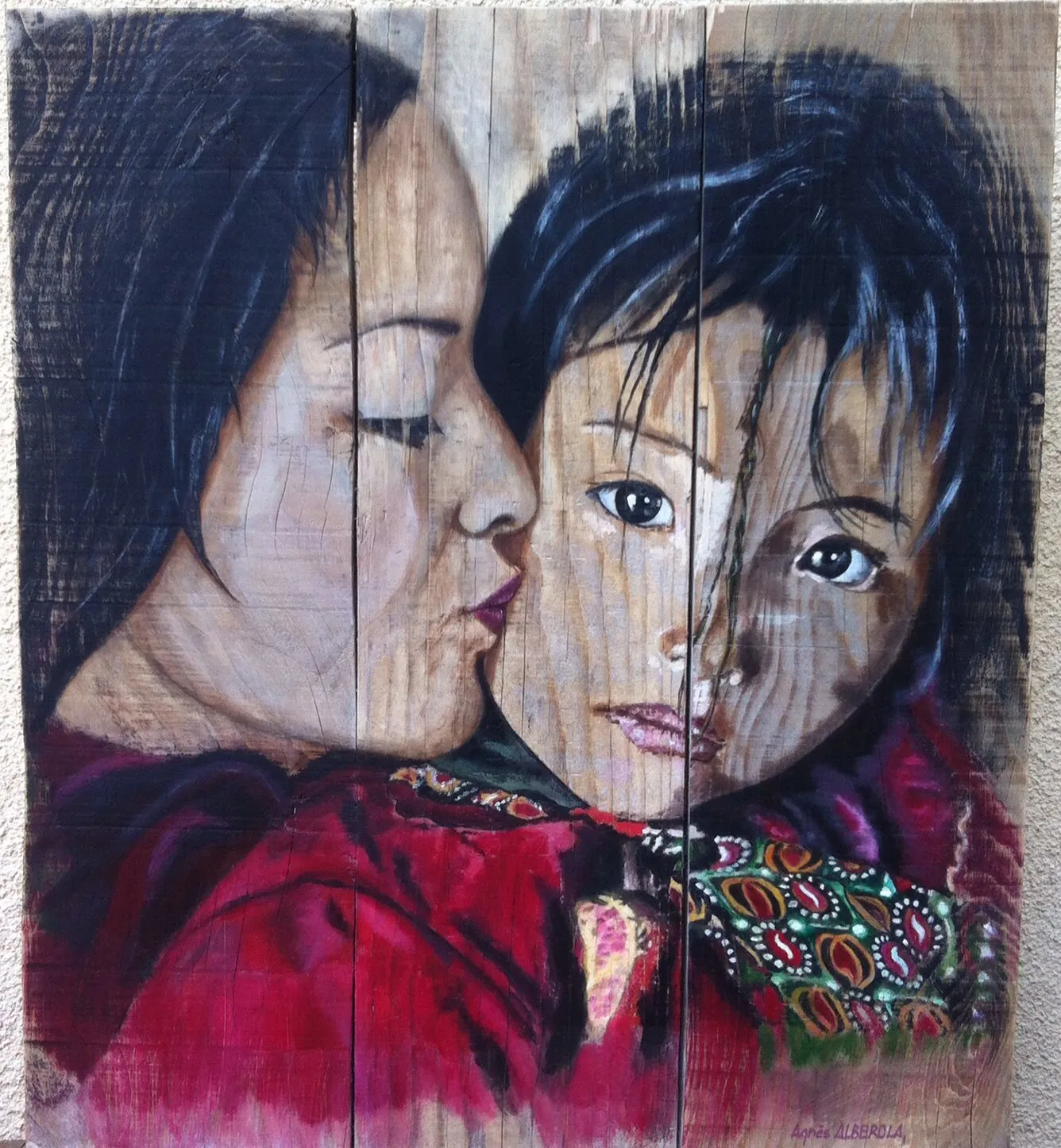 Mère embrassant un enfant, étoffe rouge sur bois brut